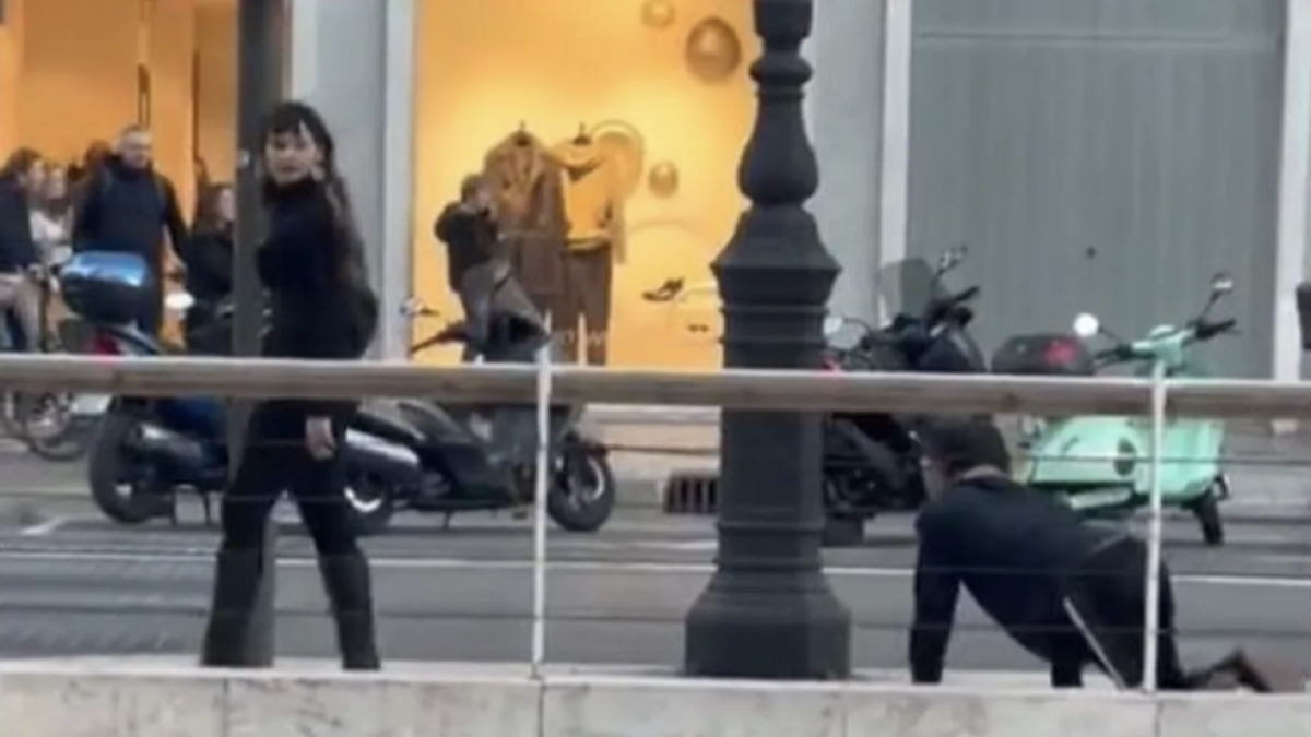 Una mujer pasea a un hombre con una correa por el centro de Valencia