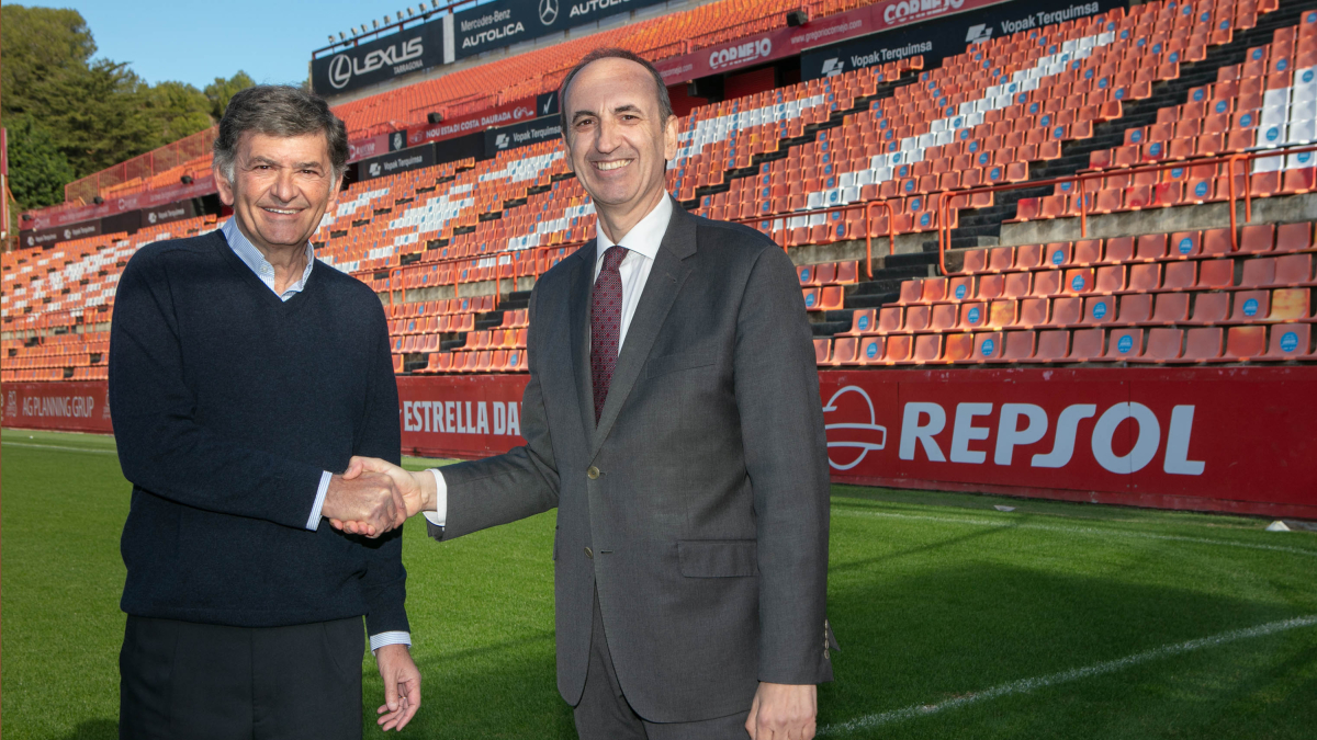 El president del Nàstic, Josep Maria Andreu i el director del Complex Industrial de Repsol a Tarragona, Javier Sancho, segellant l'acord al Nou Estadi amb un cartell publicitari de Repsol al fons.