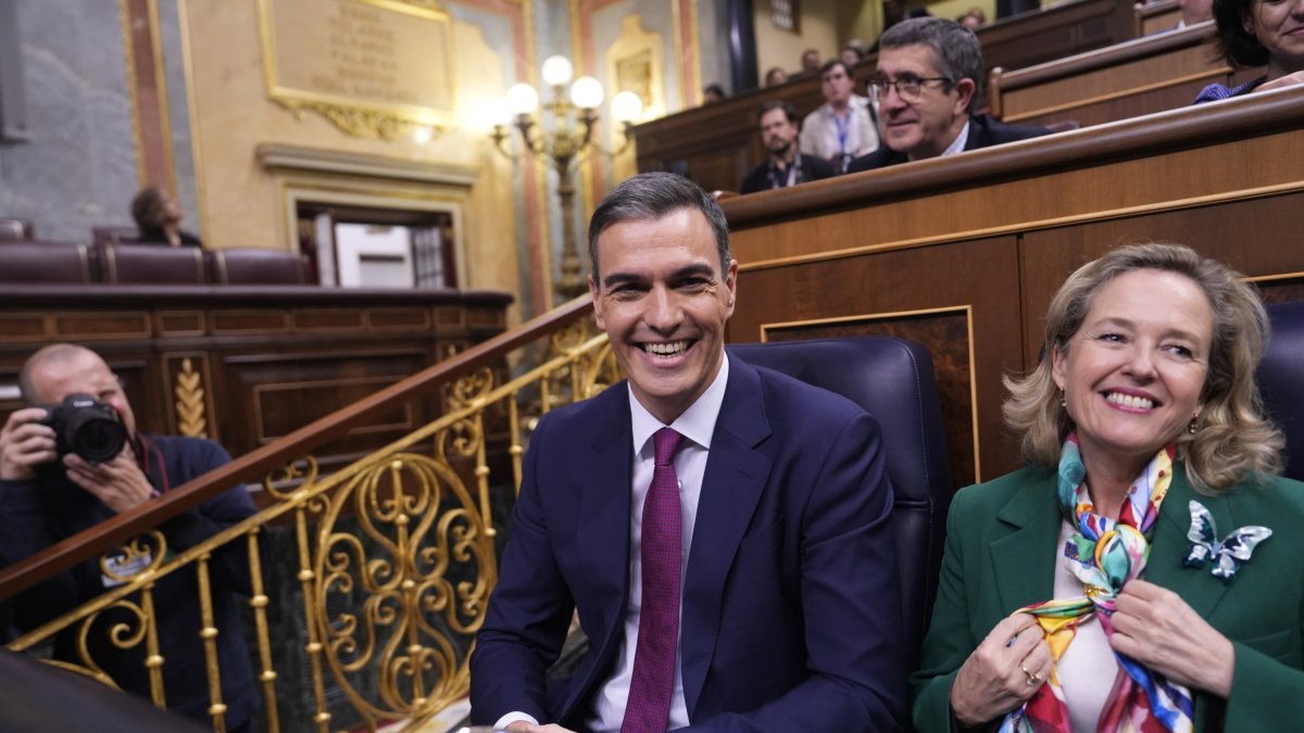 Pedro Sánchez sentado con la ministra en funciones Nadia Calviño en el lado sonriente al inicio de su debate de investidura.