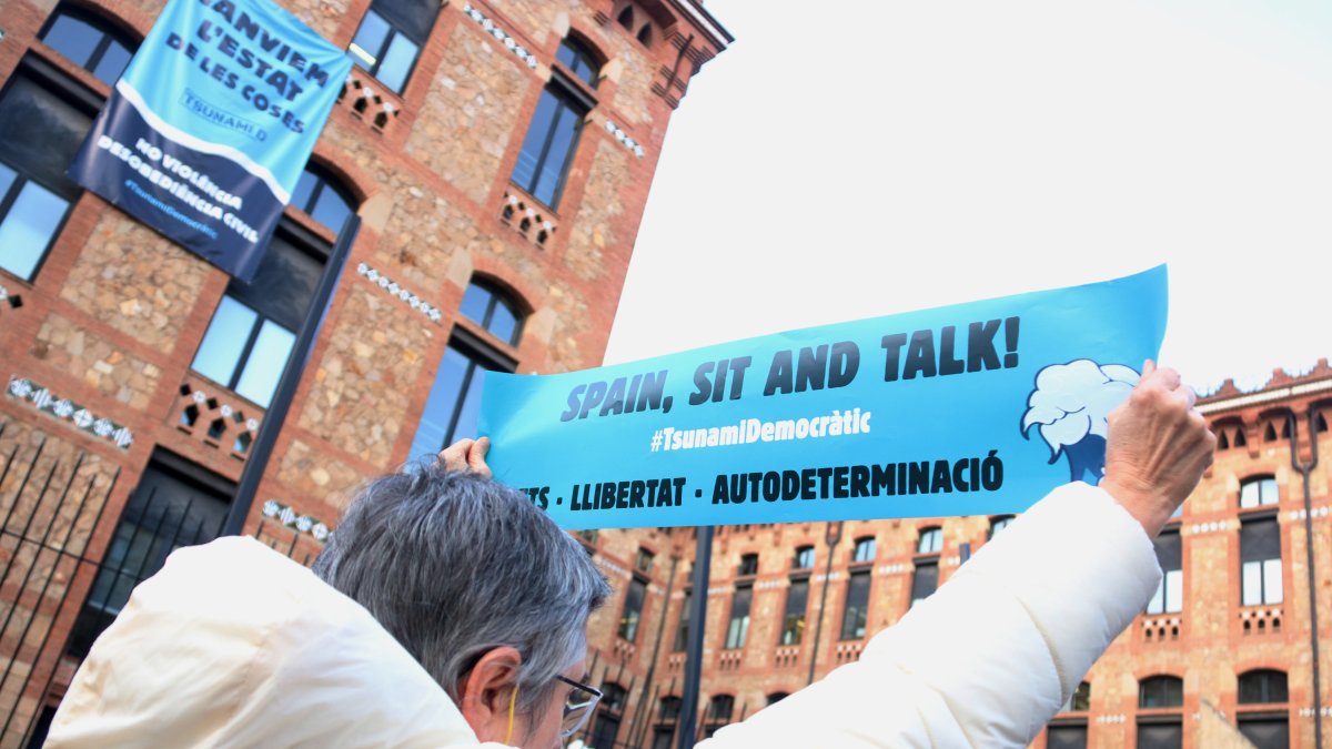 ¡Una mujer muestra un cartel de 'Spain, sit and talk!' del Tsunami Democrático.