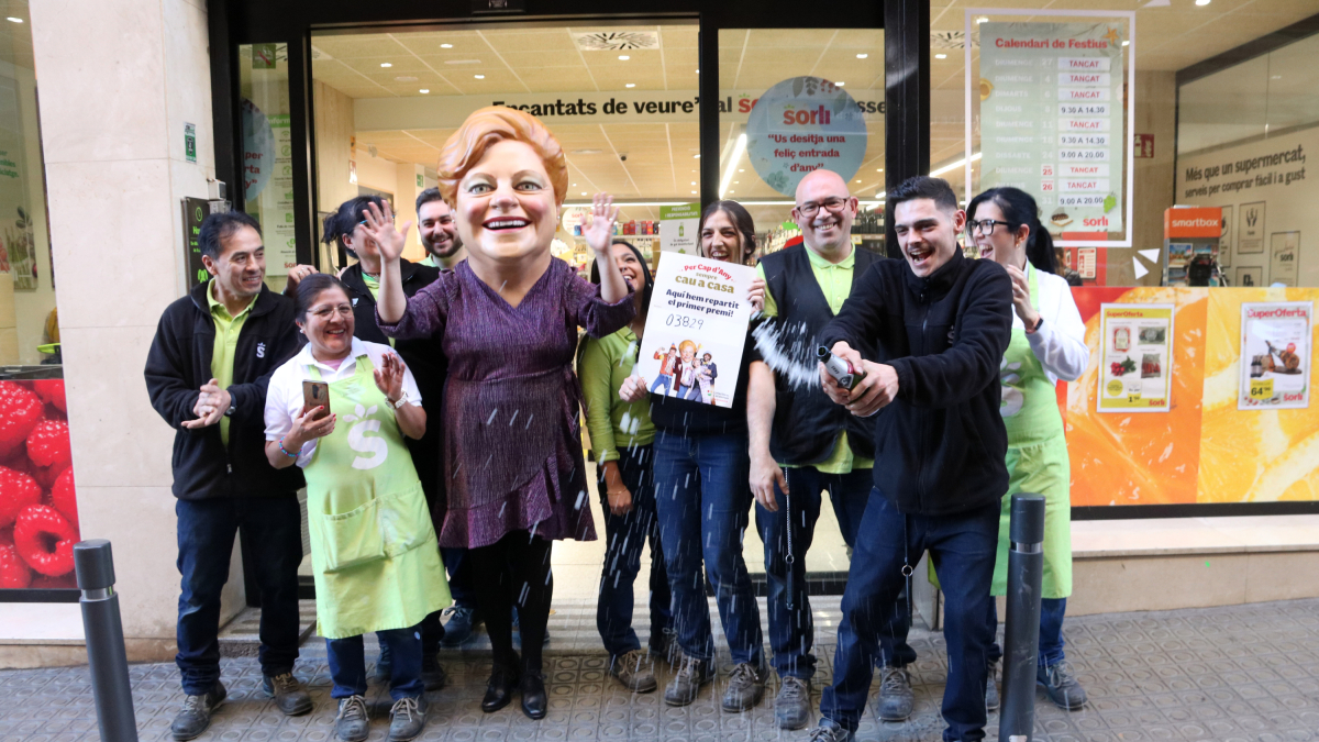 Trabajadores del supermercado Sorli de la calle de Massens de Barcelona y el cabezudo de la Grossa celebran haber repartido el primer premio.
