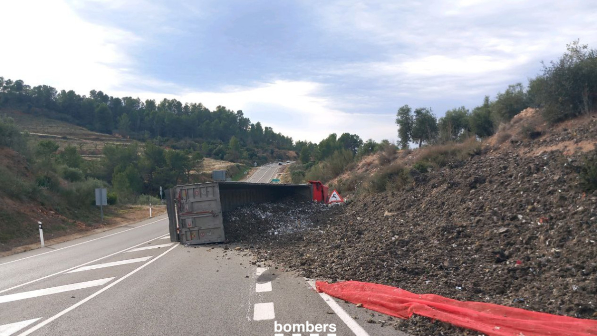 Imagen del camión volcado y con la carga extendida por la vía.