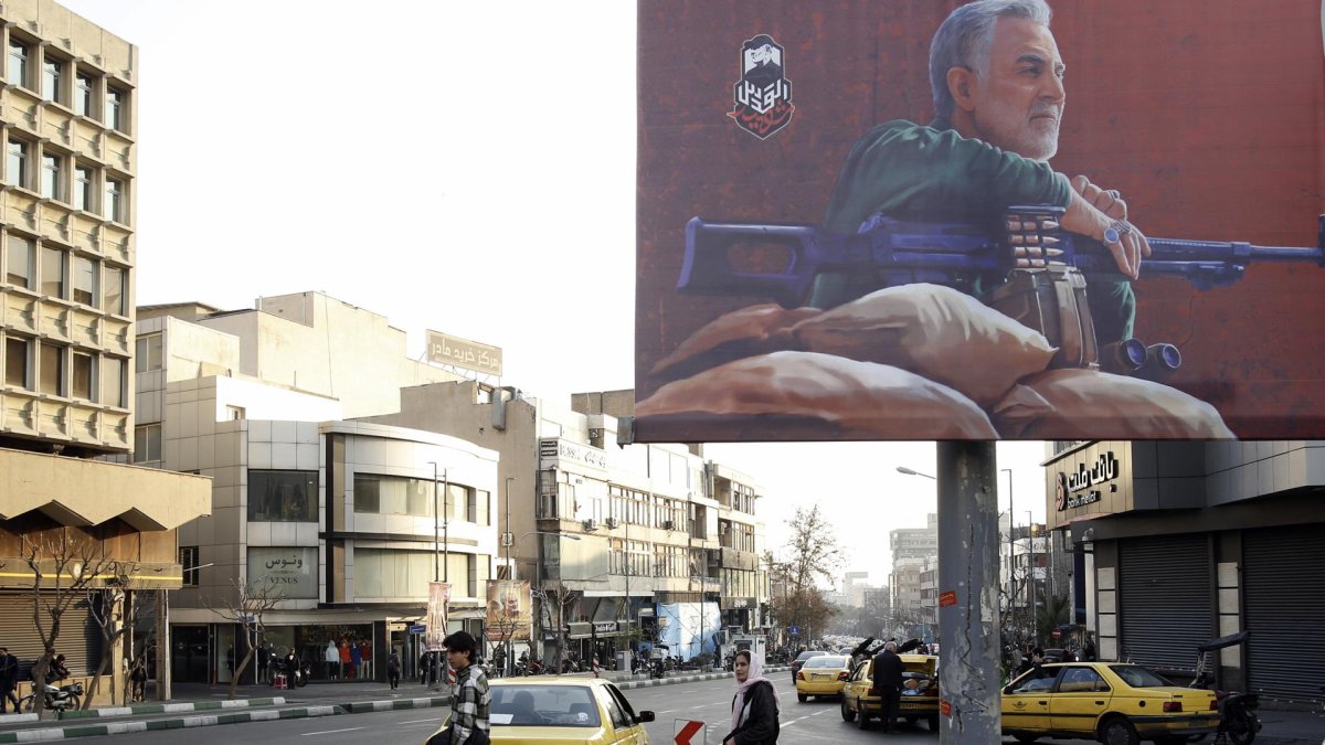 Els iranians caminen al costat d’un cartell que mostra al difunt comandant de la Guàrdia Revolucionària, Qasem Soleimani, abans del seu quart aniversari de mort.
