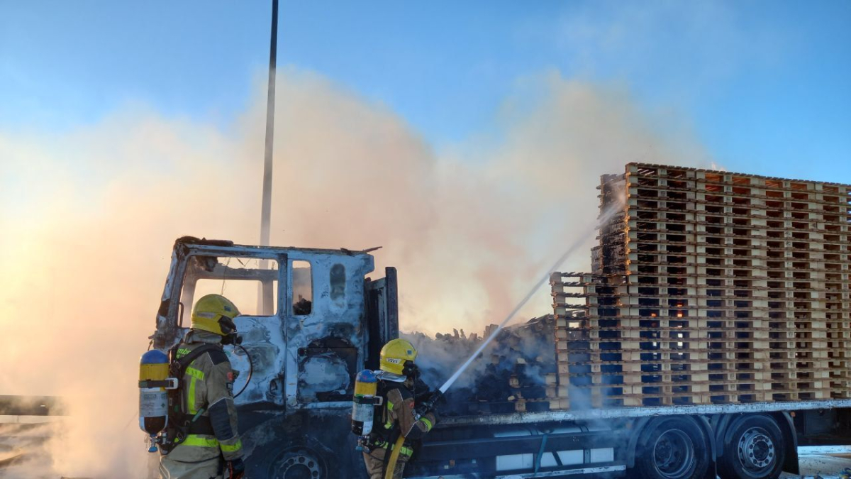 Imagen de los Bomberos apagando las llamas del camión incendiado.
