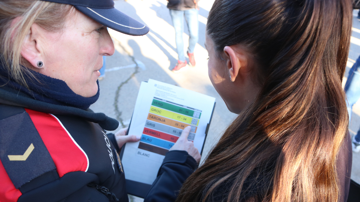 Una aspirante al cuerpo de los Mossos d'Esquadra y una agente consultando el aula donde tiene que realizar las pruebas.