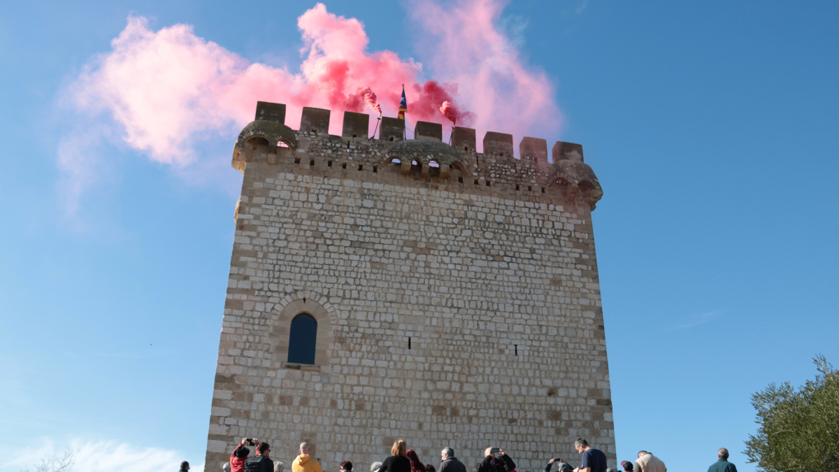 Una treintena de personas observando y fotografiando el encendido de la Torre de la Carrova d'Amposta.