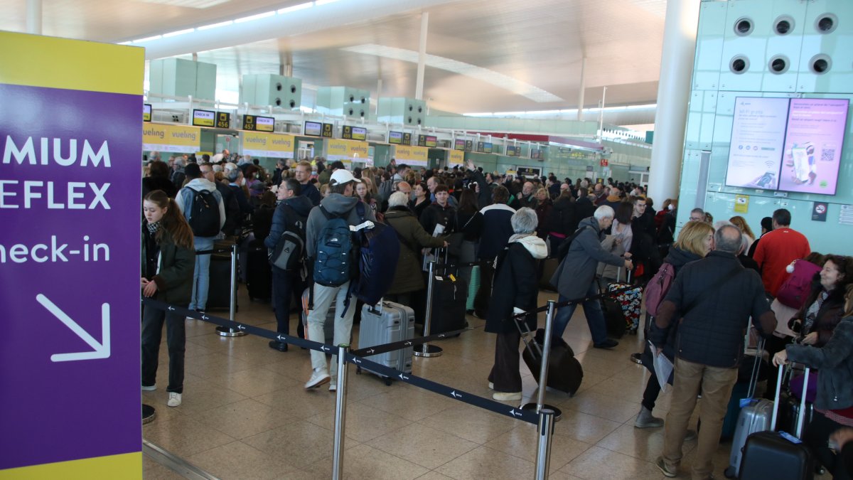 Pasajeros de Vueling hacen cola para facturar las maletas, en el aeropuerto del Prat.