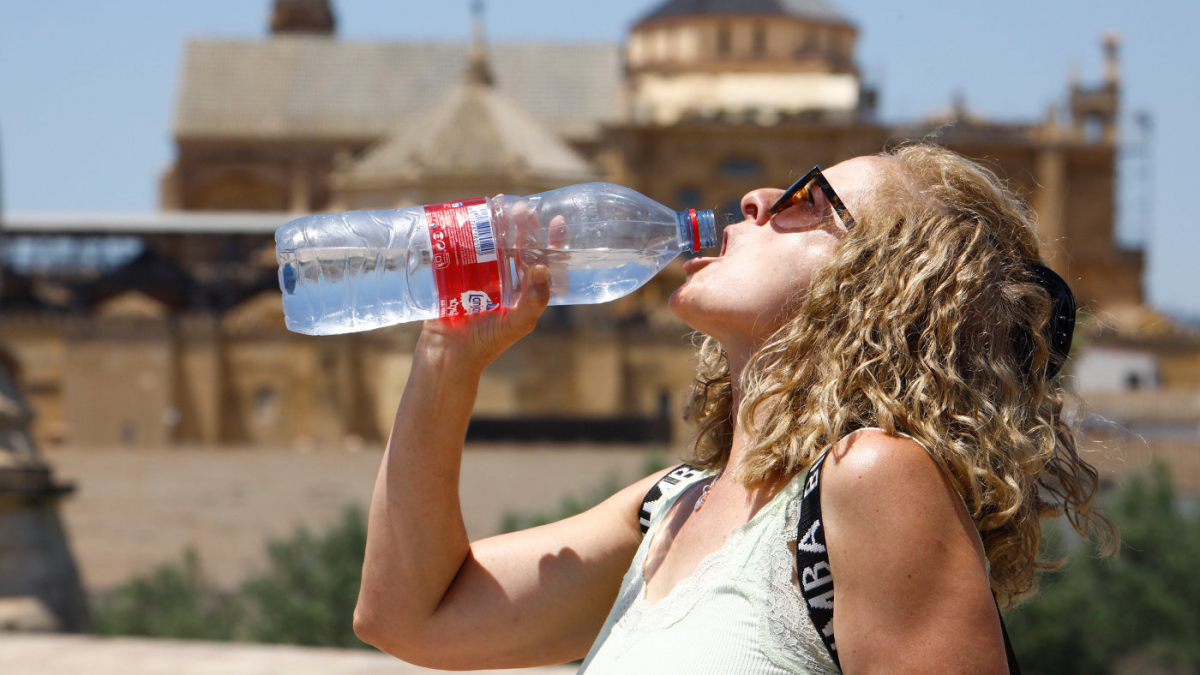 Una dona beu aigua per combatre la calor.
