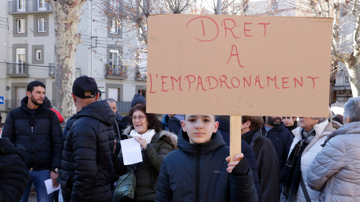 Un nen amb un cartell reclamant el dret a l’empadronament a Ripoll.