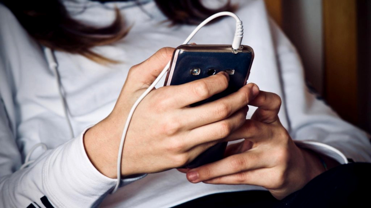Una joven mira su teléfono móvil.