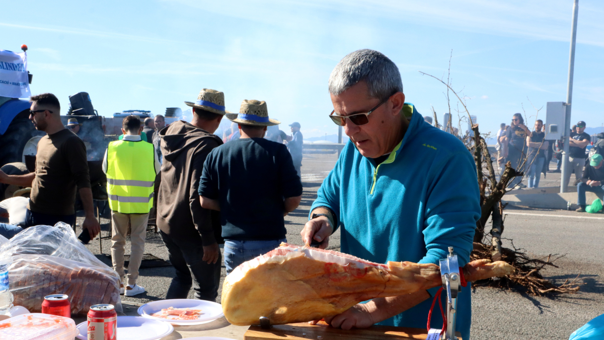 Un payés cortando jamón durante las movilizaciones en el puerto de Tarragona.