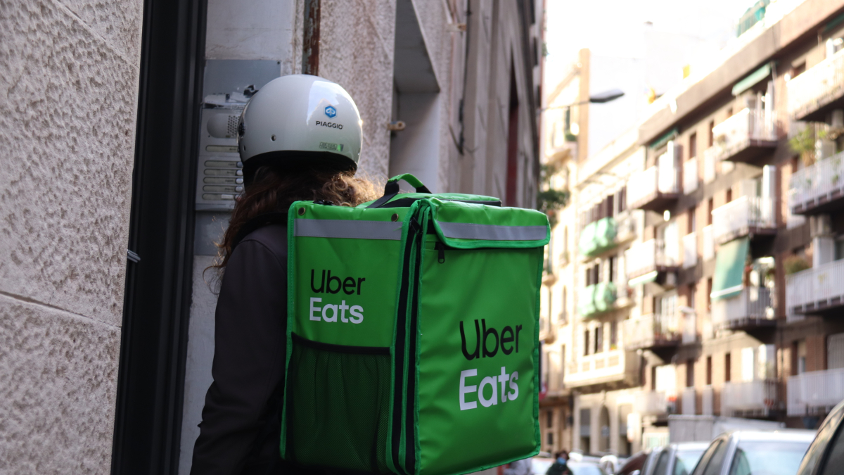 Imagen de una repartidora de Uber Eats esperando para entrar a entregar un pedido en un domicilio
