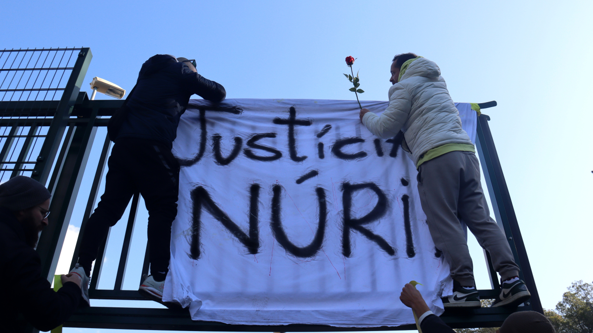 Dos trabajadores de Mas d'Enric colgando una pancarta y una rosa en las puertas del centro penitenciario.