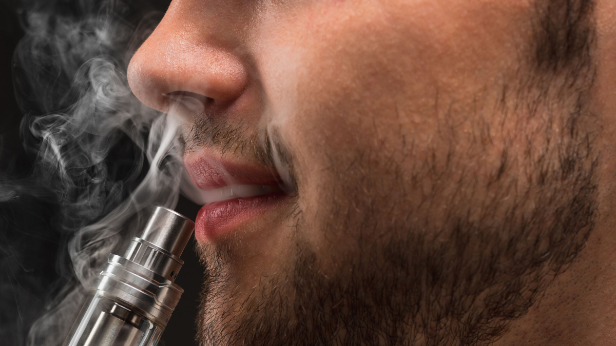 Un home aspira fum d'una cigarreta electrònica.