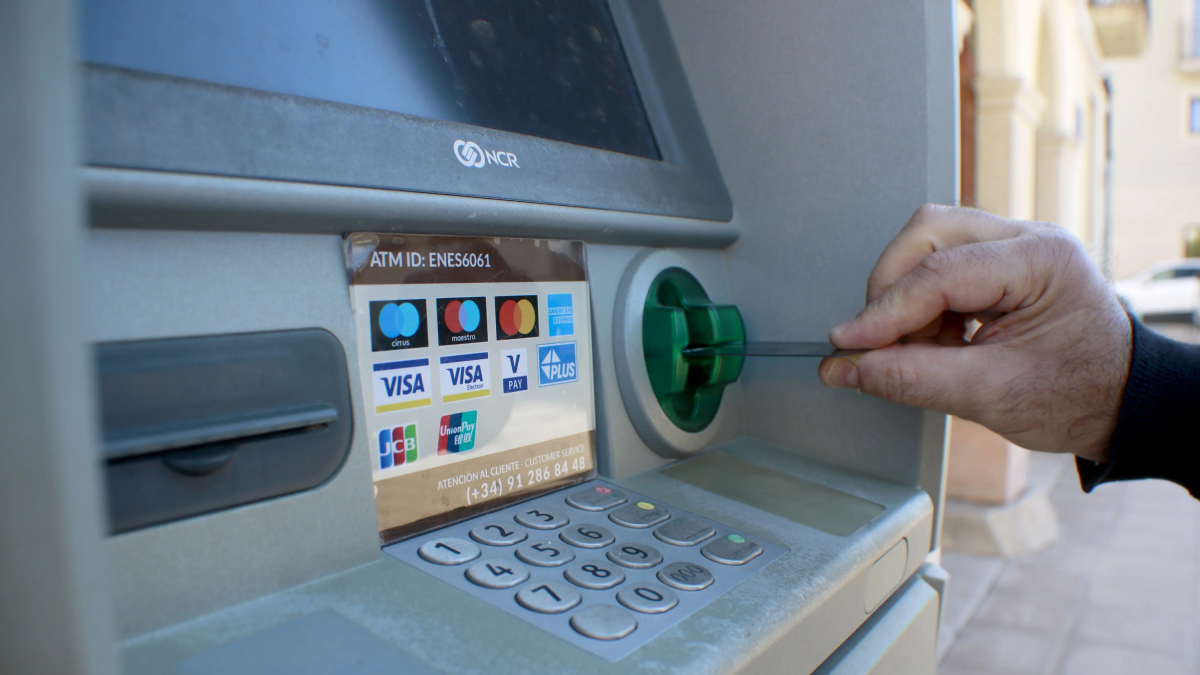 Una persona introdueix una targeta bancària en un caixer automàtic.