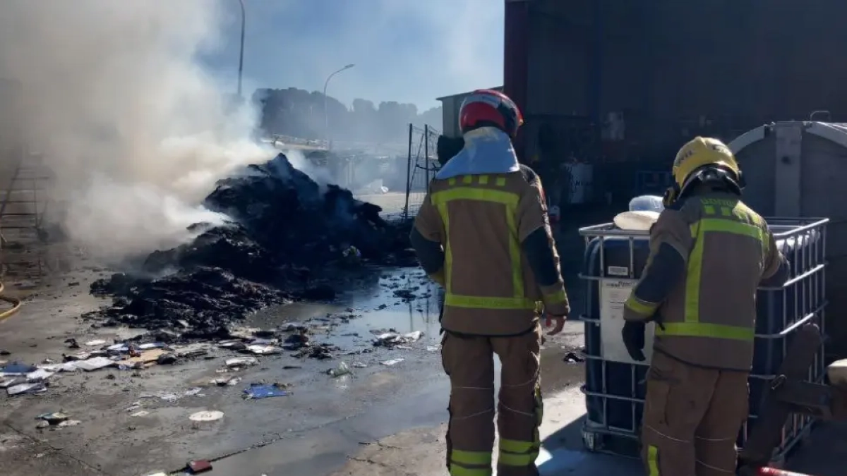 Dos bomberos en el lugar|sitio del incendio del camión de basura.