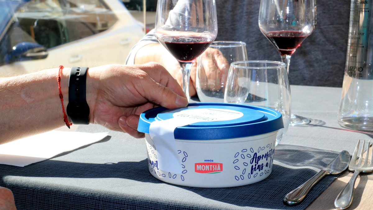 Un cliente se lleva el arroz que no se ha acabado de la comida en uno de los tupperwares de Oryzite y reutilizables de la Càmara Arrossera del Montsià.