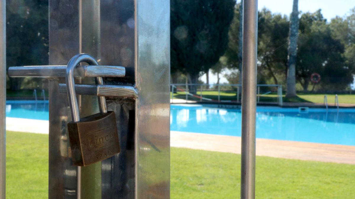 Un candado bloquea el acceso a la piscina de un camping