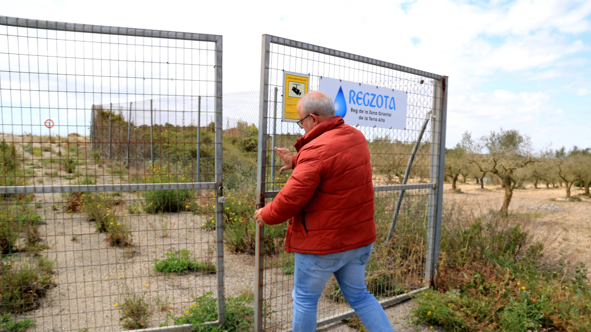 Un treballador obre la tanca d'una bassa de reg de la comunitat de regants de la Terra Alta.
