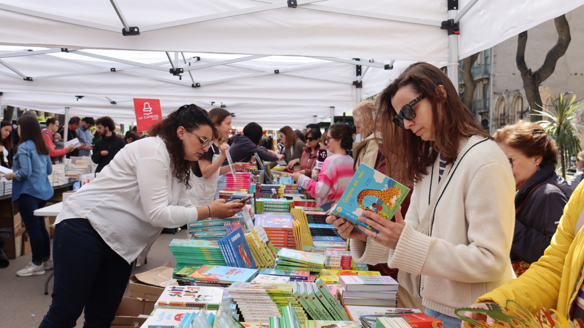 Varias personas mirando libros en la parada de La Capona en Tarragona.