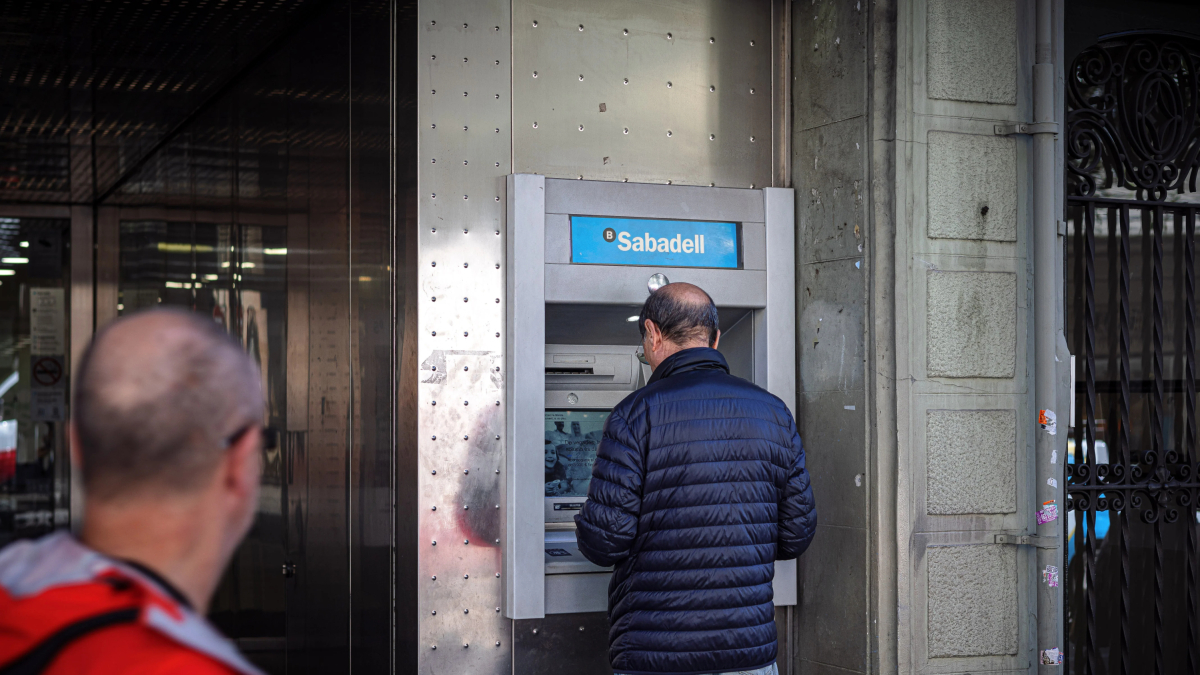 Un hombre saca dineros de un cajero automático del Banc Sabadell