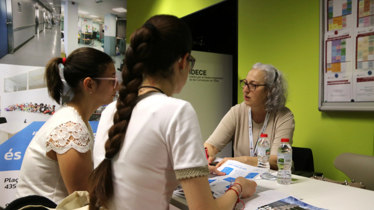 Dos chicas entrevistándose con la Clínica Terres de l'Ebre en la Feria de Ocupación de la URV.