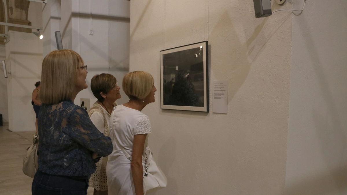 Tres mujeres observan una fotografía incluida en la muestra 'Horta Picasso Mont-roig Miró' en la iglesia vieja de Mont-roig del Camp.