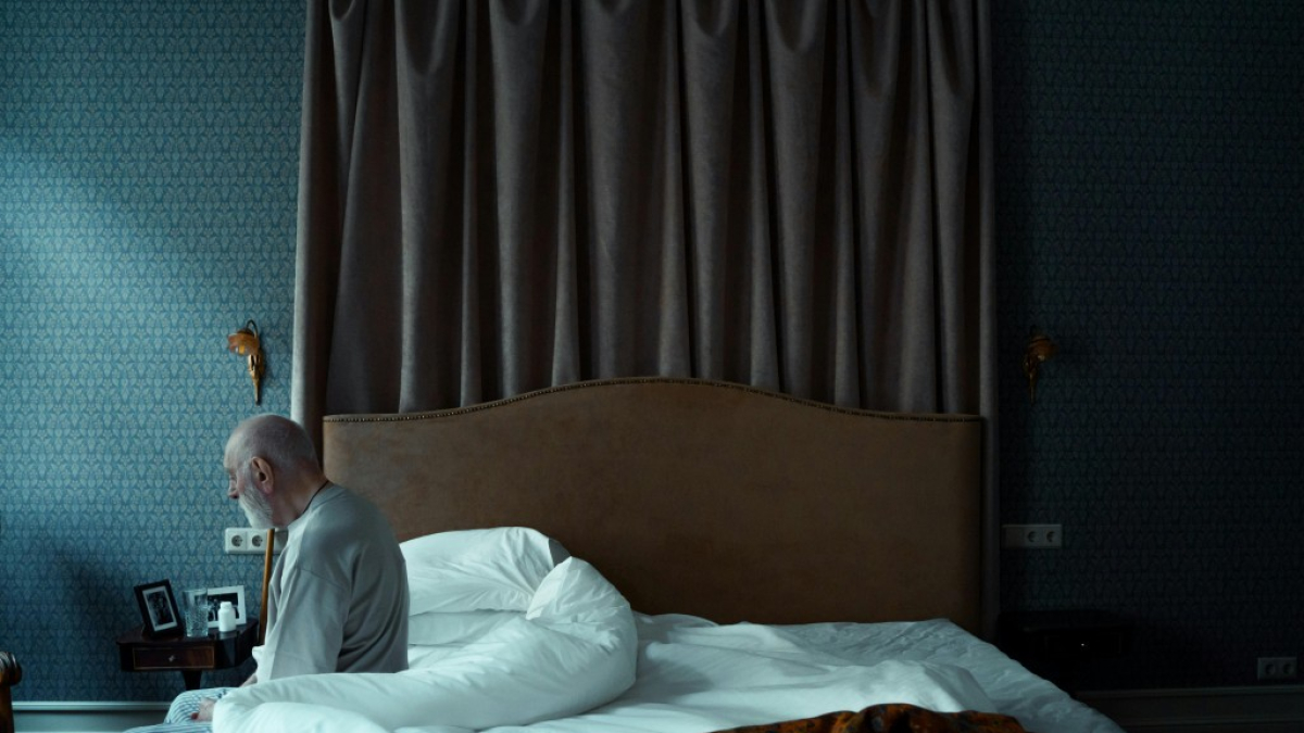 Una persona mayor sentado en una cama.