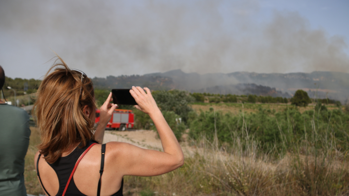Una mujer fotografía el incendio que ha obligado a evacuar un camping de Montblanc.
