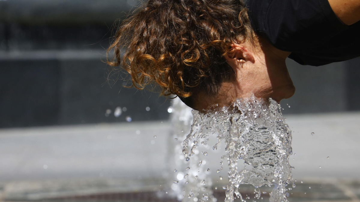 Una turista se refresca en una fuente.