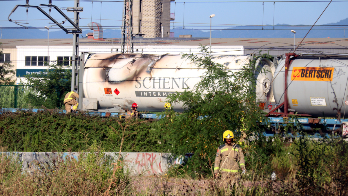 Los Bombers al lado del vagón del tren de mercancías que se ha incendiado en Girona.