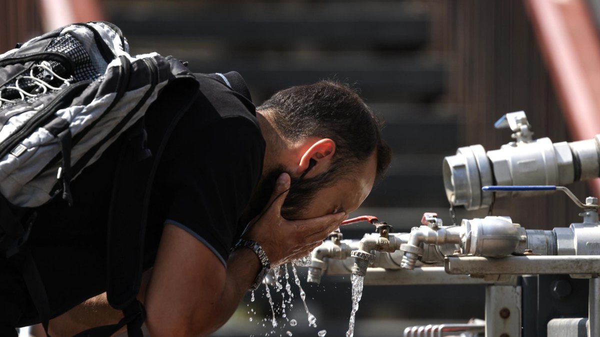 Imagen de una persona refrescándose en una fuente.