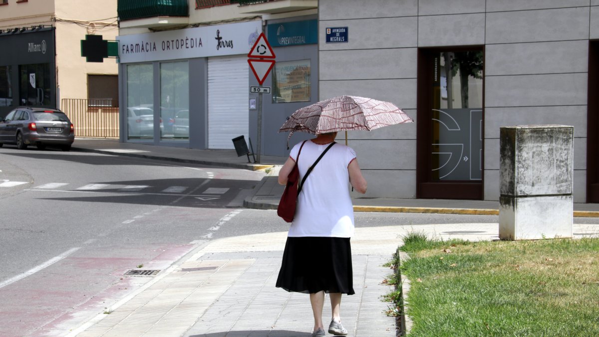 Una persona pasea por Mollerussa con un paraguas para protegerse del sol.