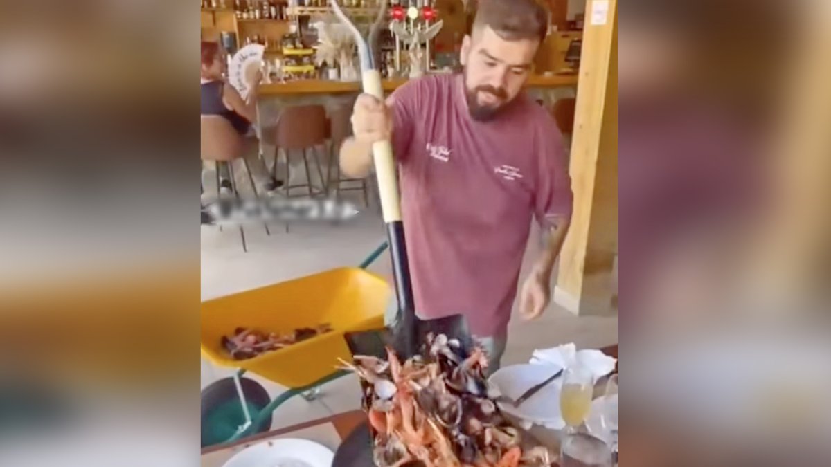 Imagen del camarero sirviendo marisco con una carretilla y una pala.