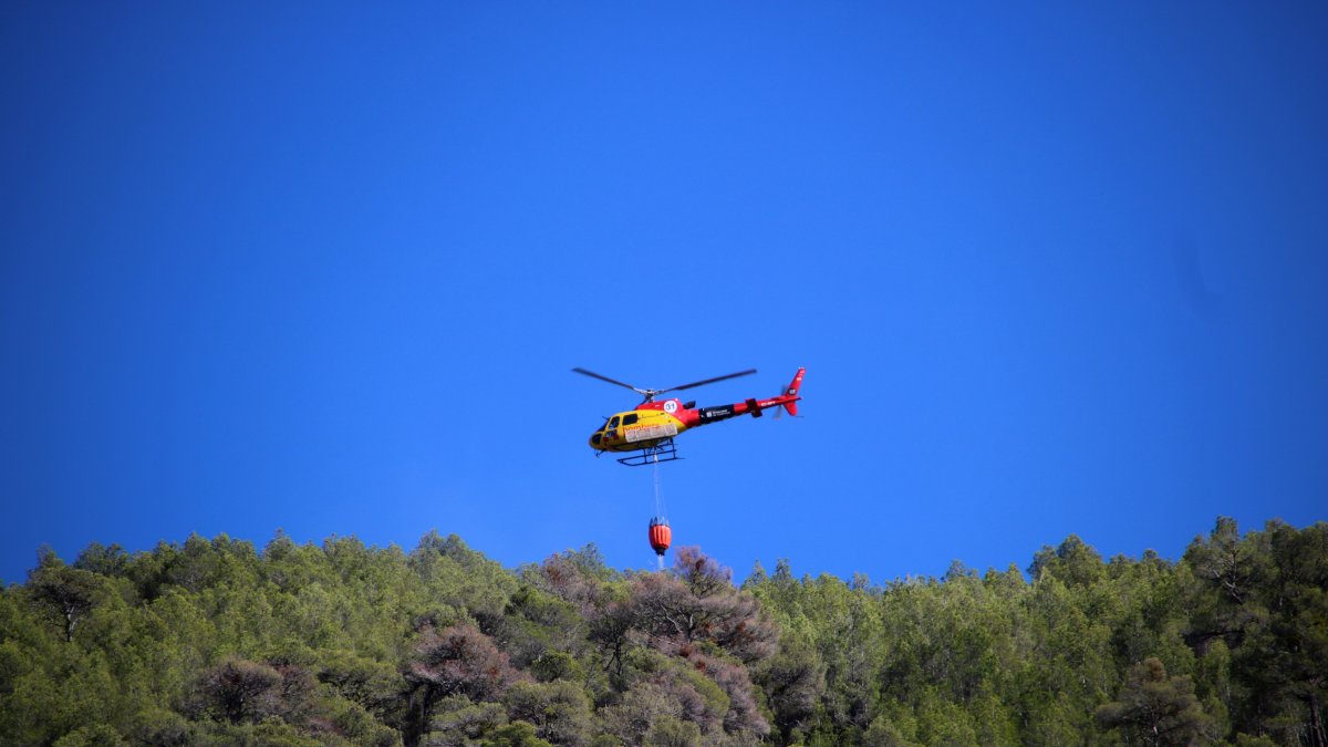 Un helicóptero bombardero tirando agua en una de las zonas afectadas por el incendio de Cabacés.