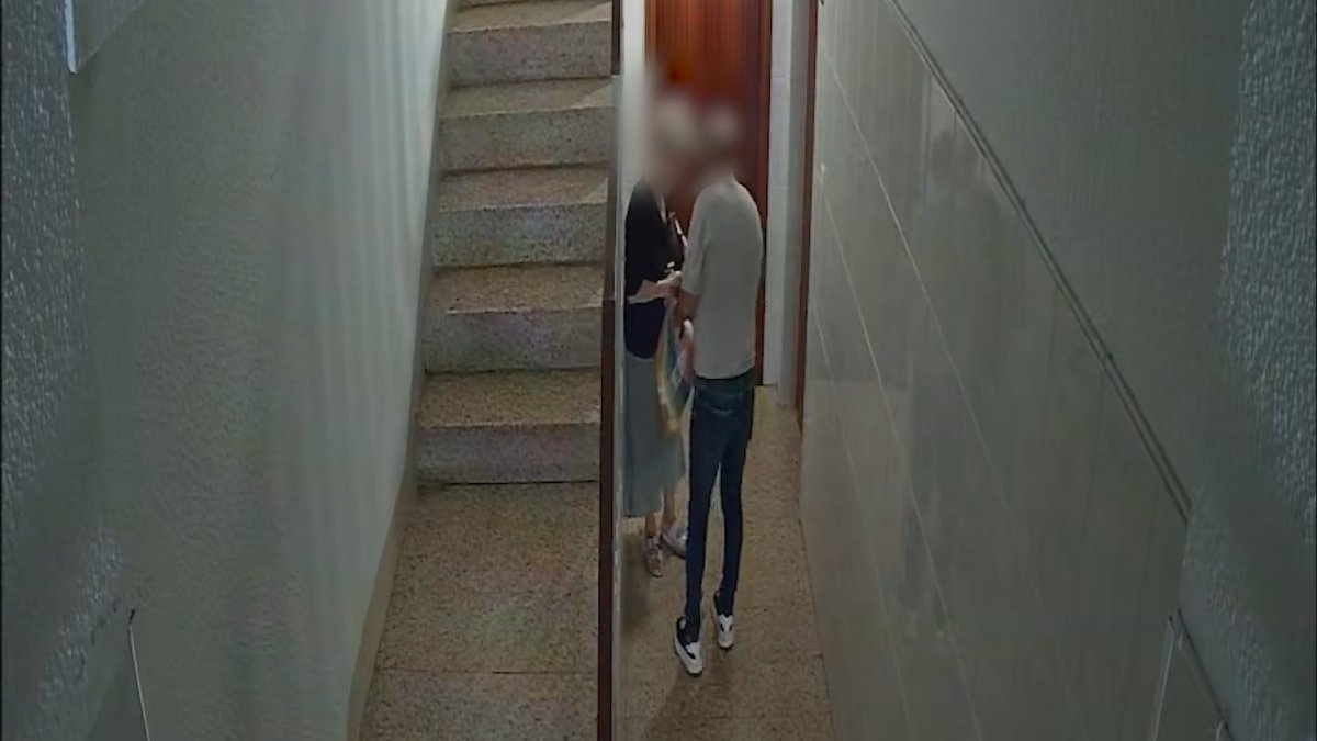 Captura d'una càmera de seguretat on es pot veure al lladre atracant a una dona gran a punta de navalla.