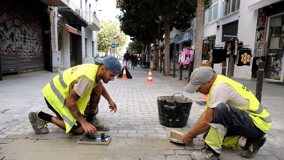 Dos operaris arreglant el paviment d’un carrer de Cambrils.