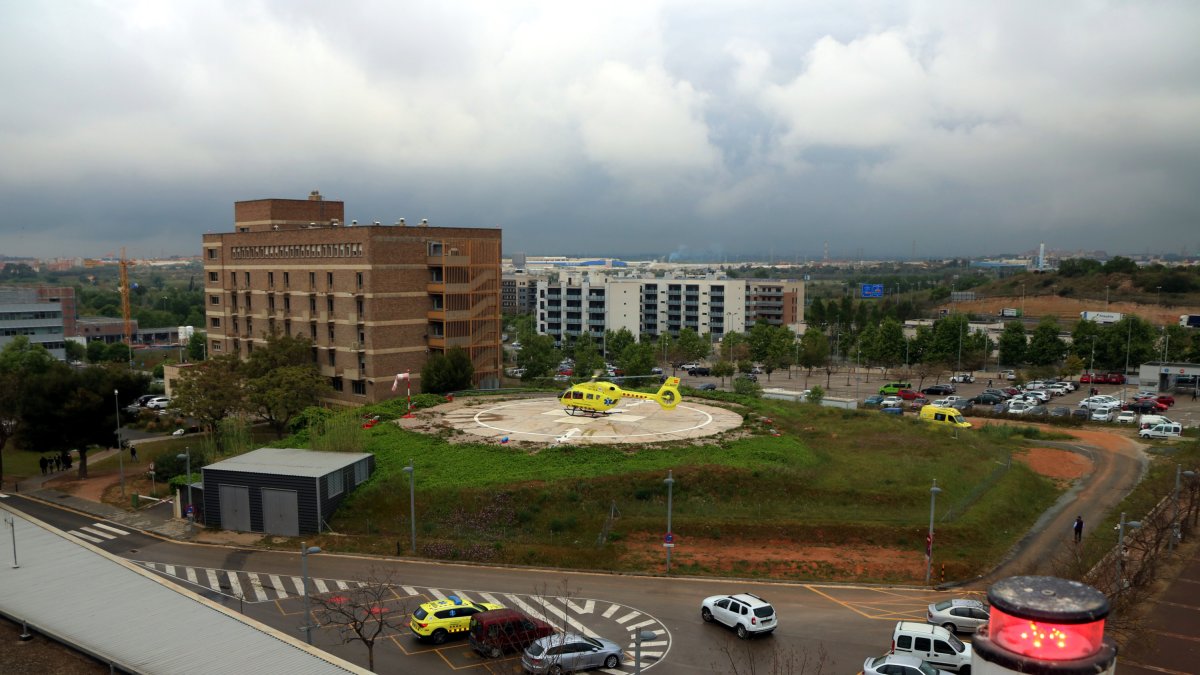 Gran pla general de l'helisuperfície de l'hospital Joan XXIII de Tarragona amb un helicòpter medicalitzat aparcat i una balisa lluminosa en primer terme. Imatge del 28 d'abril del 2021. (Horitzontal)