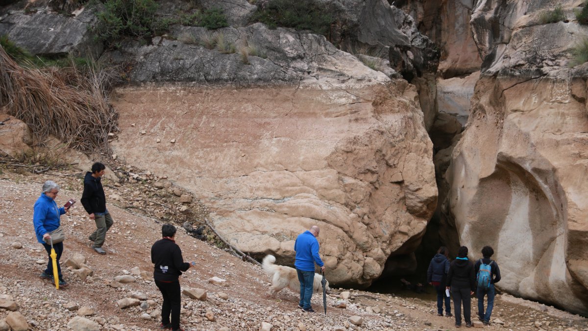 Un grup de persones baixen fins a la bassa dels Estrets del riu Canaletes, gairebé buida