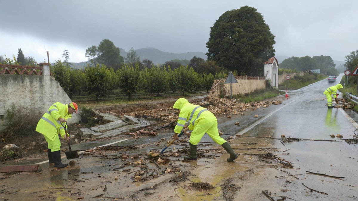 Unos operarios limpiando la carretera de acceso a Manuel cortada por la DANA.
