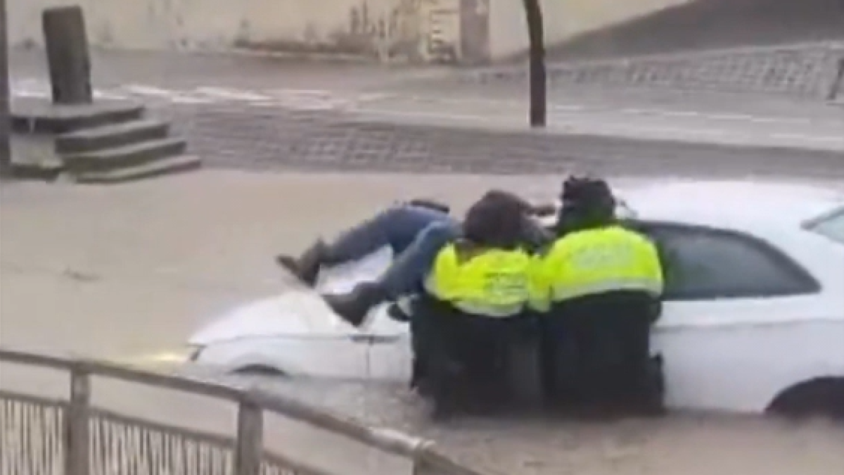 Tres efectius dels Mossos d'Esquadra rescaten el conductor d'un vehicle atrapat en una zona inundada a la carretera C-32, al seu pas per Castelldefels.