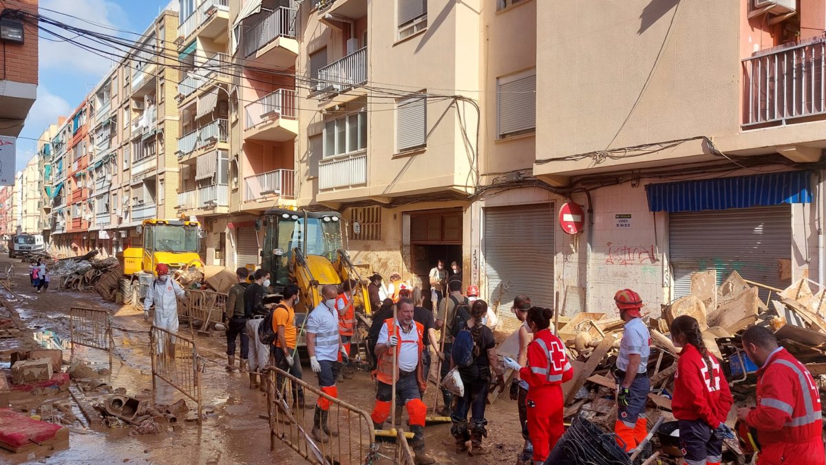 Voluntarios de Cruz Roja limpiando una de las calles afectadas por la DANA.