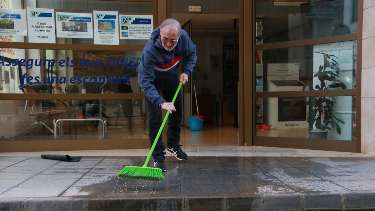 En Paco, veí d'Alcanar, retira aigua del seu local després de l'aiguat torrencial.