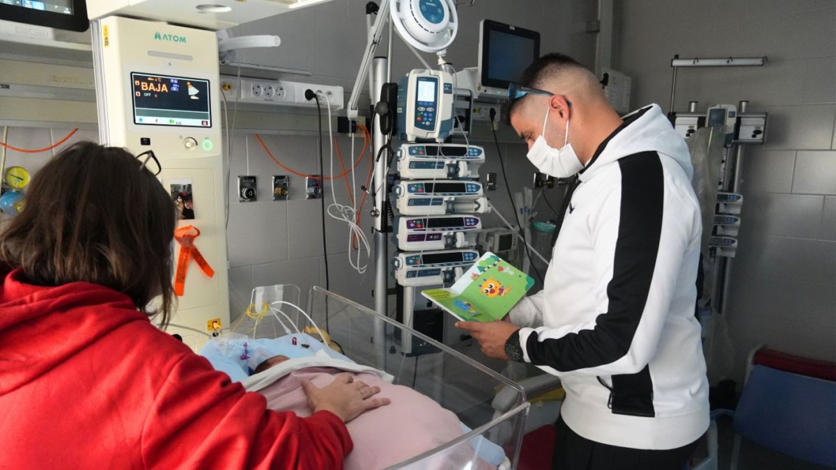 El padres de un niño prematuro leyéndole un cuento.