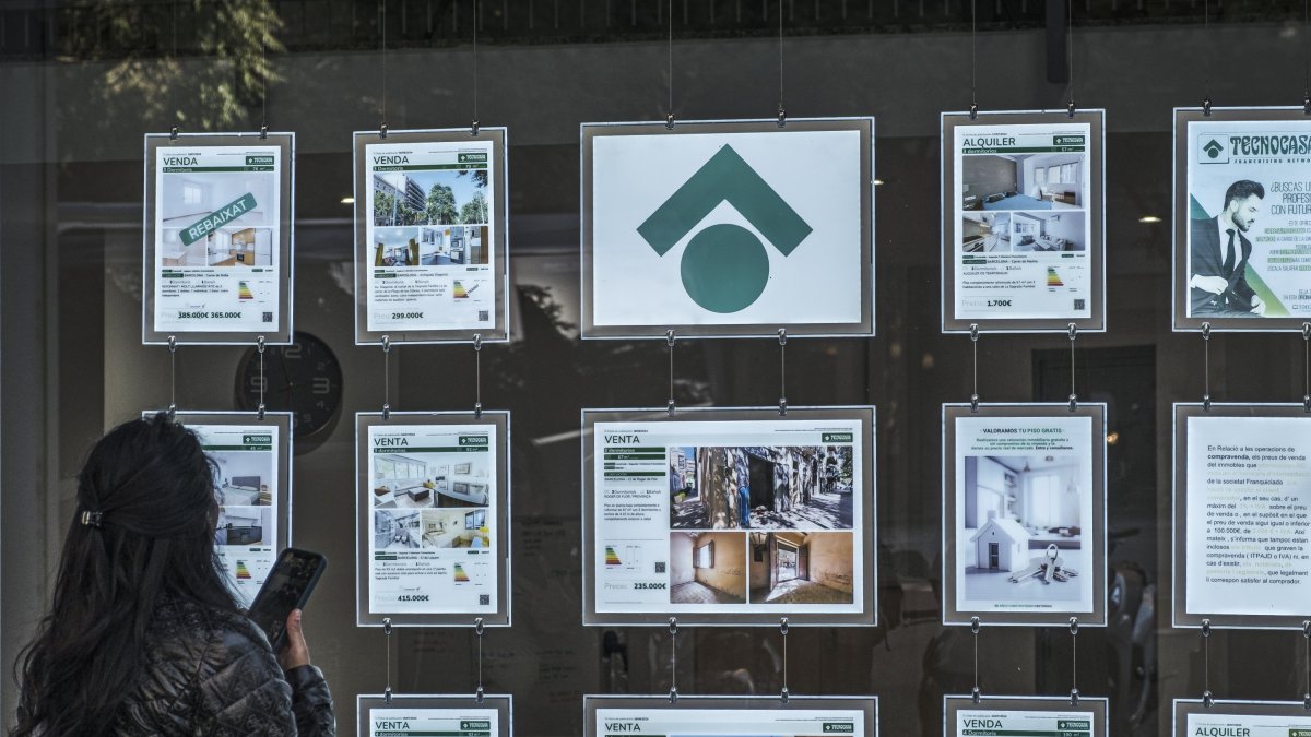 Una mujer revisa los anuncios de viviendas expuestos en una inmobiliaria