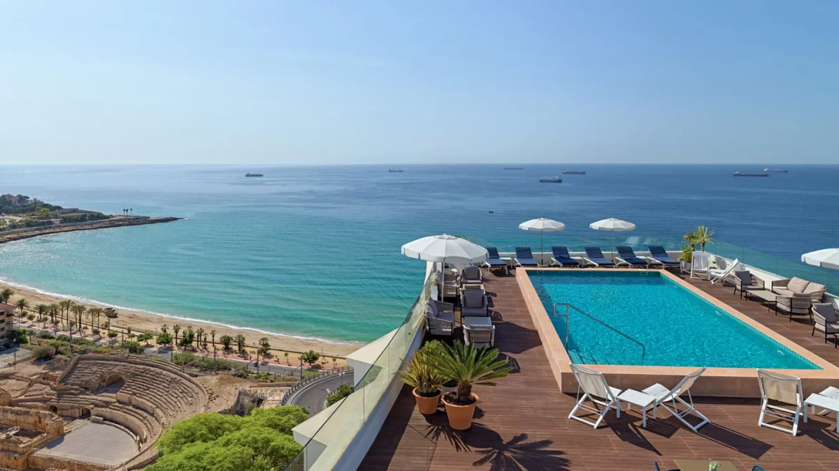 Imagen de la piscina en el terrado del Hotel H10 Imperial Tarraco, con vistas en el anfiteatro romano de Tarragona y el Mar Mediterráneo.