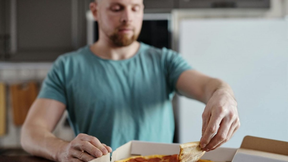 Un home menjant pizza.