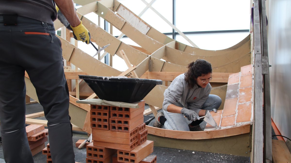 Fotografía de archivo de una mujer albañil haciendo una demostración de la construcción de un tejado.