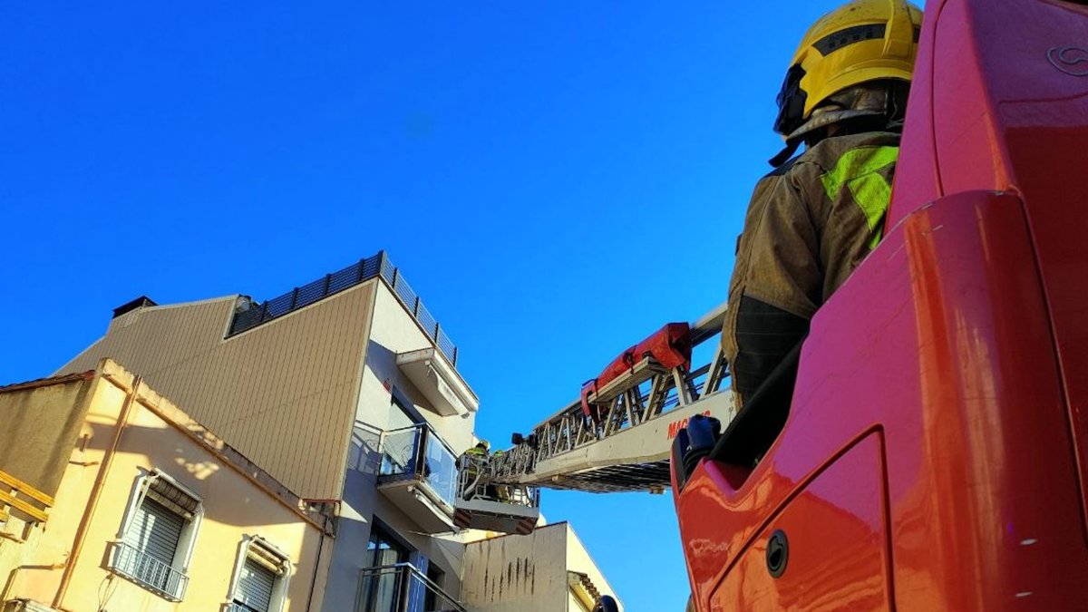 Una grua dels Bombers de la Generalitat treballa en la façana d'un edifici de Mataró afectada pel vent.