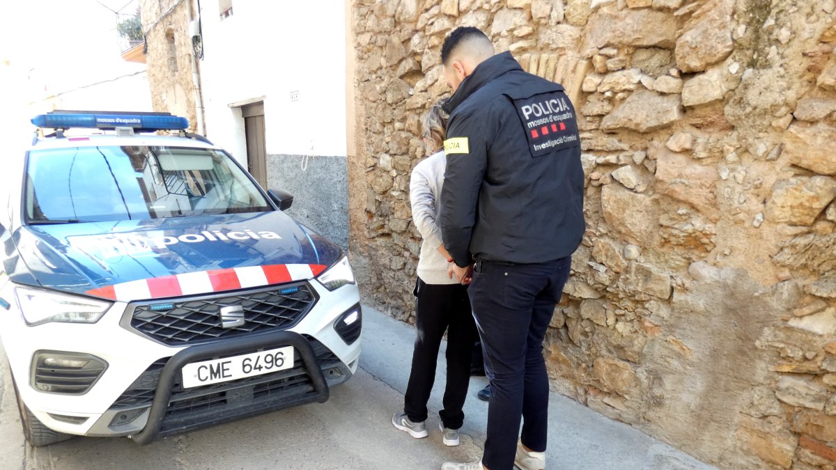 Un agente de los Mossos se lleva detenida a una mujer en Tivissa